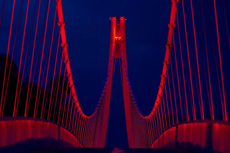 Pješački most preko rijeke Drave u Osijeku osvijetljen crvenom bojom 