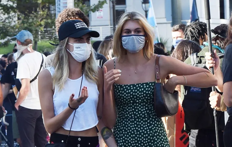 Margaret Qualley and Cara Delevingne walk hand in hand as they and Kaia Gerber attend a BLM protest in Downtown LA